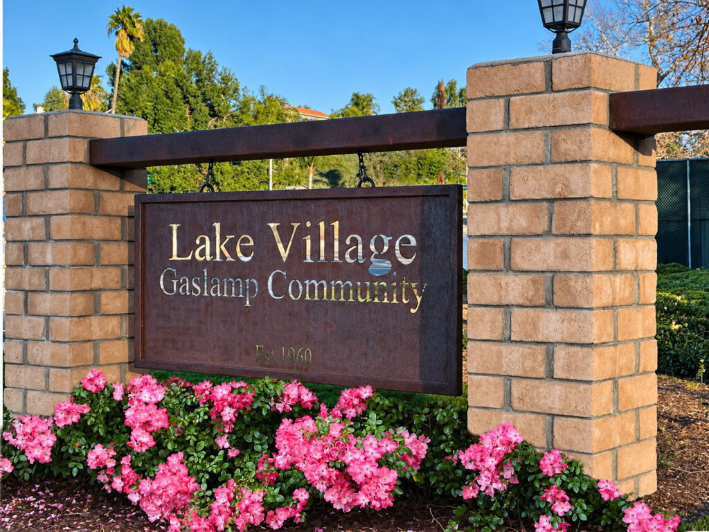 Lake Village entrance sign with pink flowers.